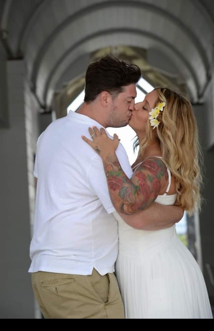 A bride and groom kissing under a white archway